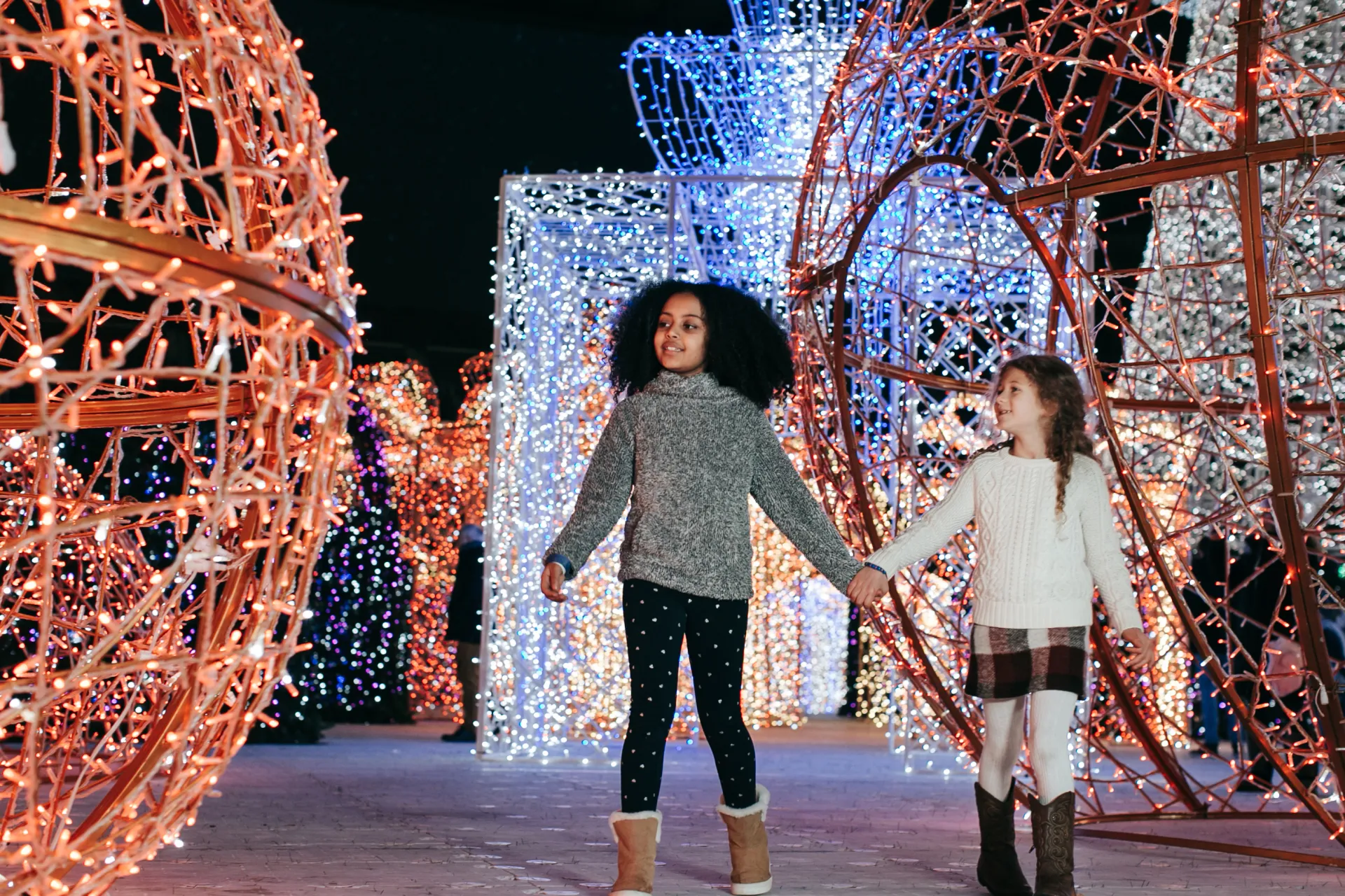 Two children walking among the large ornament light sculputures