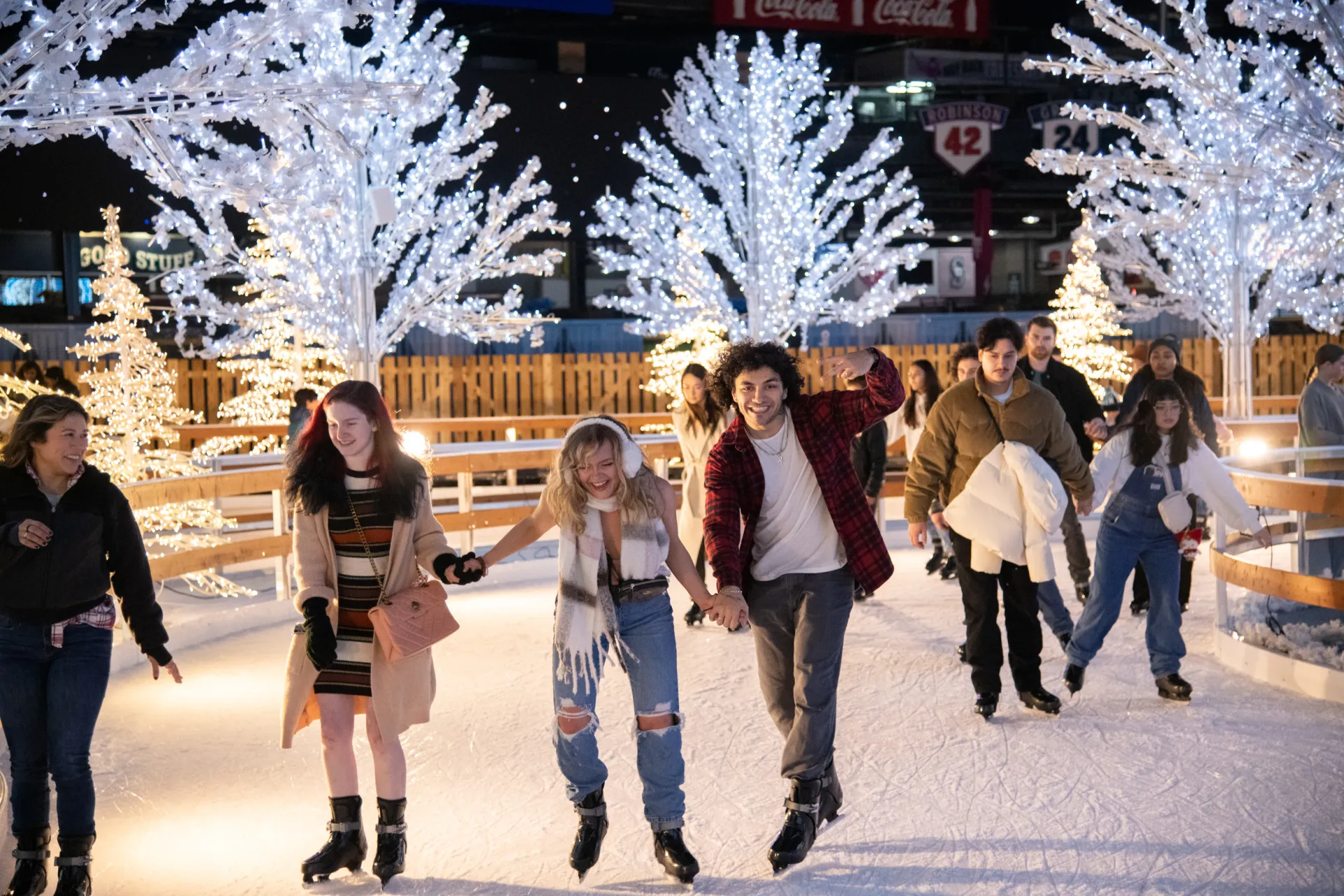Group of people ice skating with lighted trees in the background